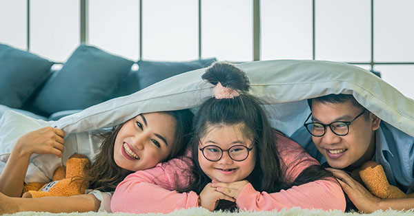 Female child with disability next to her parents smiling  