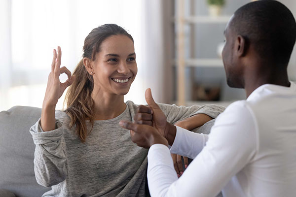 Male and female facing each other communicating in sign language. 